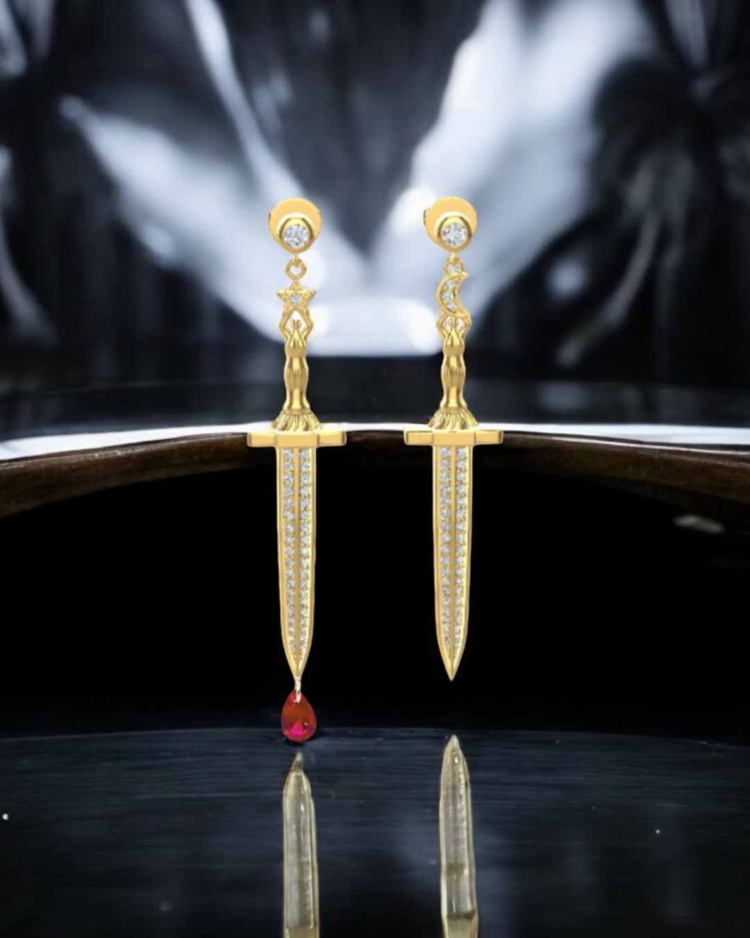 Vermeil or sterling silver Bloodstone Blade Earrings featuring a lab ruby blood drop with white or black moissanite accents on a striking sword design.
