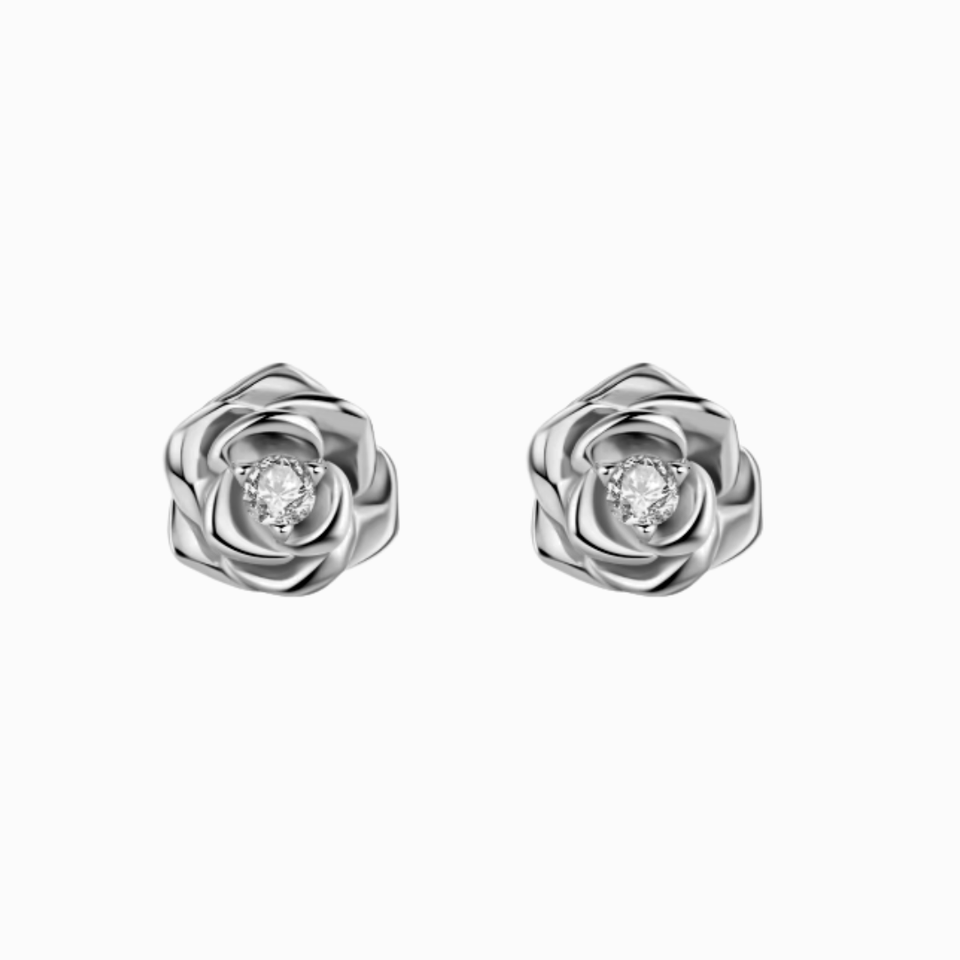 A pair of sculpted rose stud earrings in white gold or rose gold-plated sterling silver, each featuring a brilliant moissanite center stone.