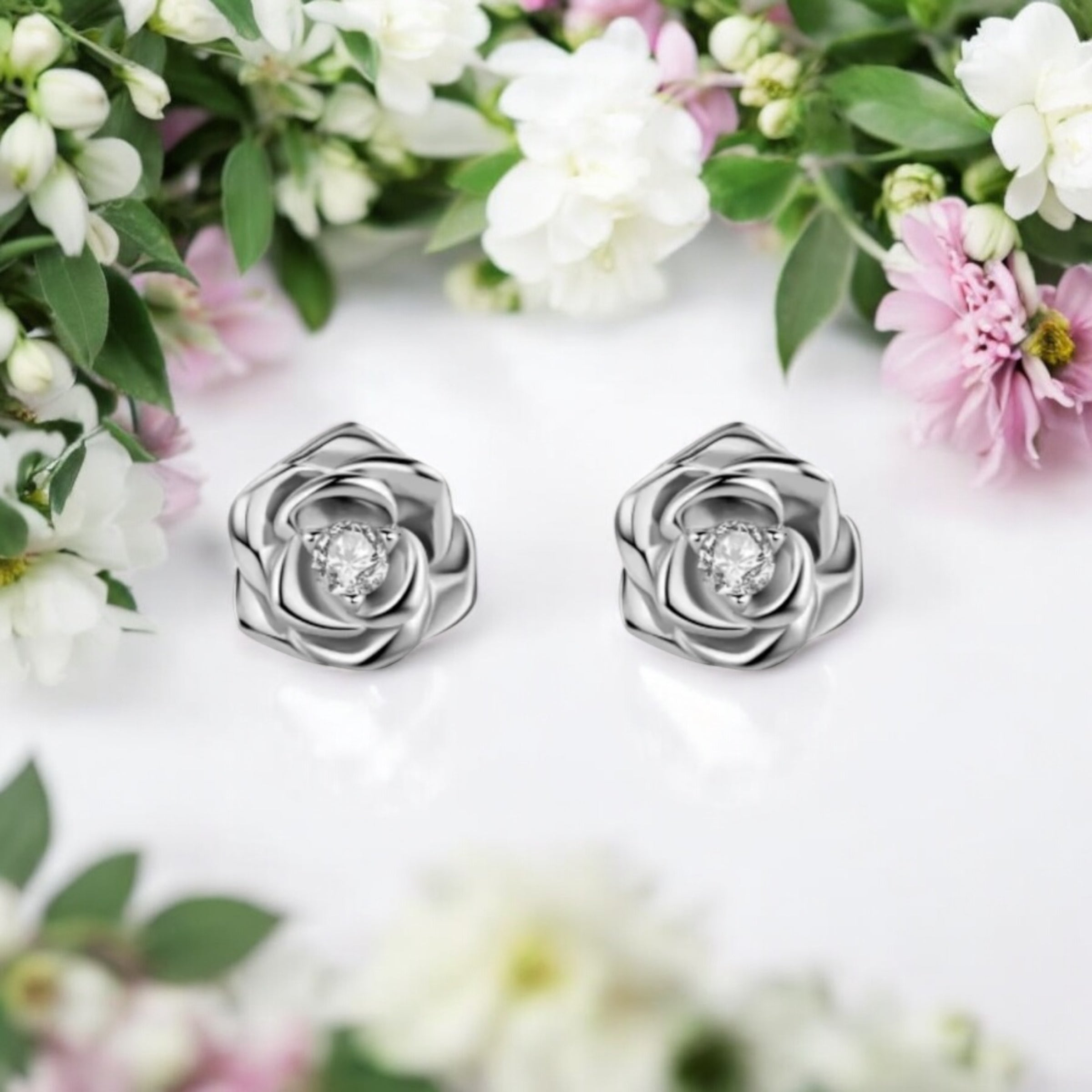 A pair of sculpted rose stud earrings in white gold or rose gold-plated sterling silver, each featuring a brilliant moissanite center stone.